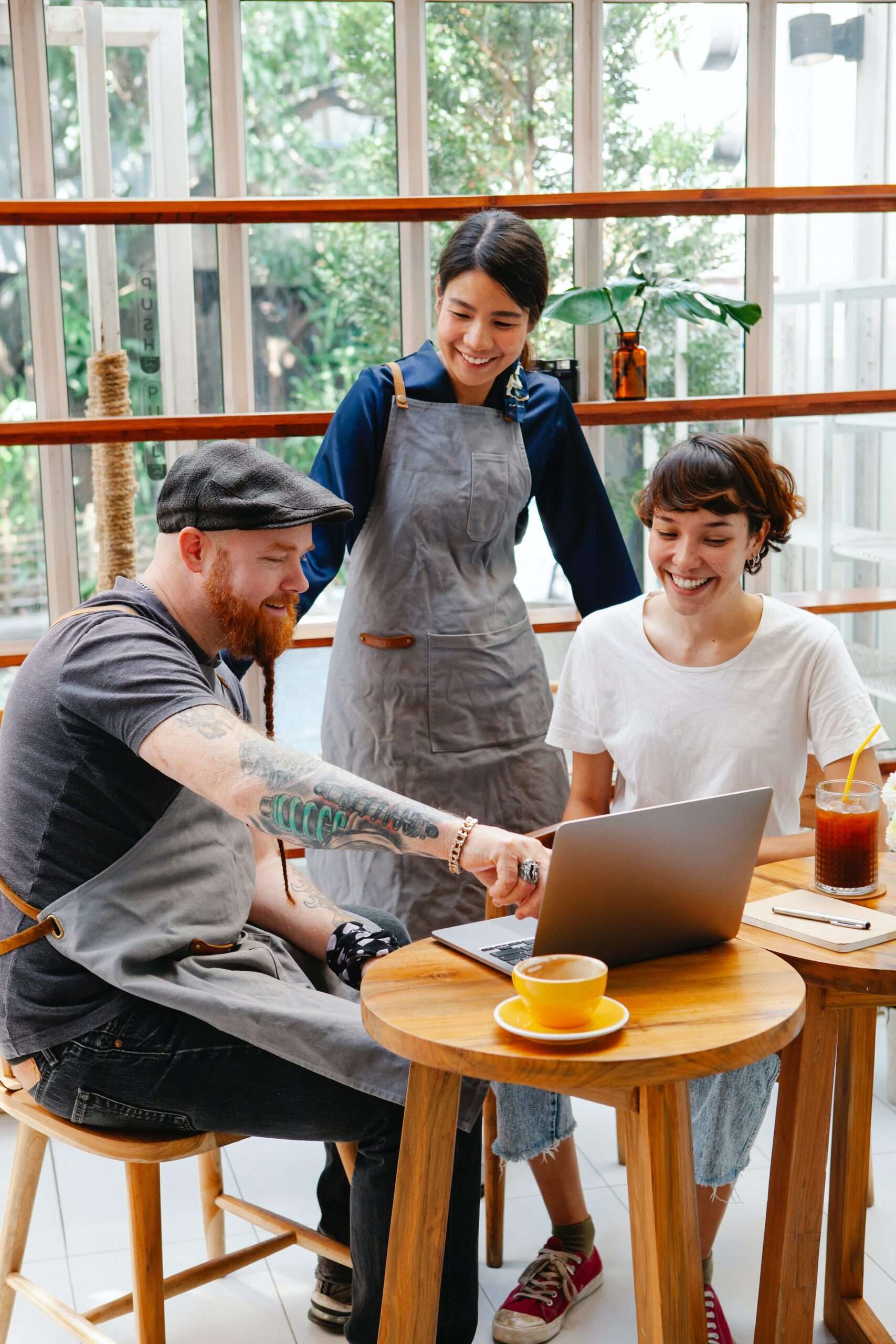The image is of 3 persons, one man and two women, talking in front of a laptop. 